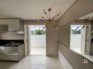 Interior de uma sala de estar com cozinha e portas de vidro que dão acesso a uma área externa.