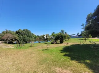 Vista de uma área gramada com árvores e água em Lajeado, Brasil.