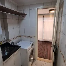 Foto de um ambiente interno com azulejos brancos e máquina de lavar.