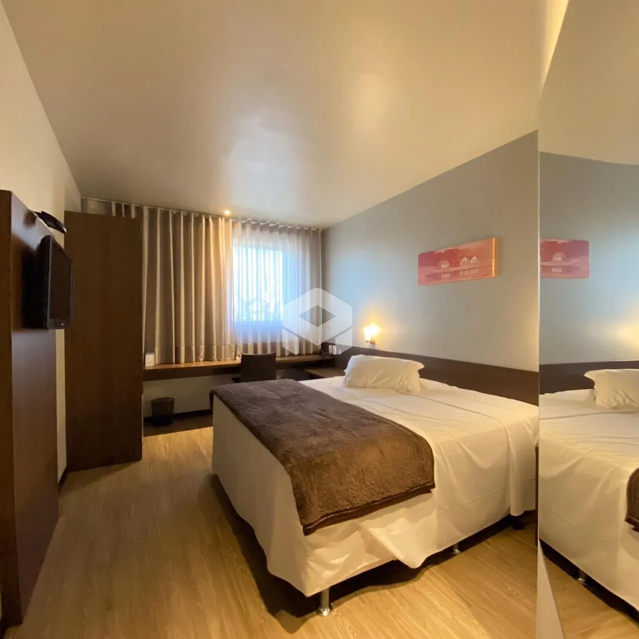 Quarto com cama de casal e piso de madeira clara.