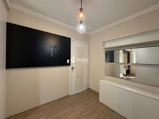 Sala de estar com piso de madeira e parede escura.