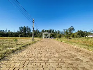 Uma estrada pavimentada se estende por uma paisagem de campo sob um céu azul.