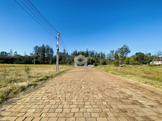 Uma estrada pavimentada se estende por uma paisagem de campo sob um céu azul.