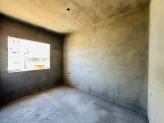 Interior de um cômodo com paredes de concreto aparente e um projeto arquitetônico exposto.