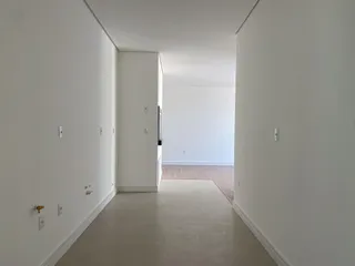 Vista de um corredor interno com paredes brancas e piso claro.