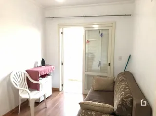 Quarto com paredes brancas e piso de madeira clara.