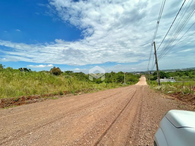 Uma estrada de terra se estende por uma paisagem verde sob um céu azul.
