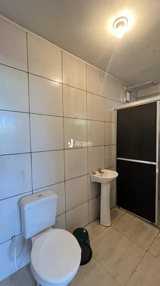 Foto de um banheiro com azulejos brancos e vaso sanitário branco.