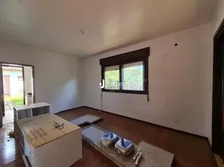 Interior de uma sala com piso de madeira e janela.