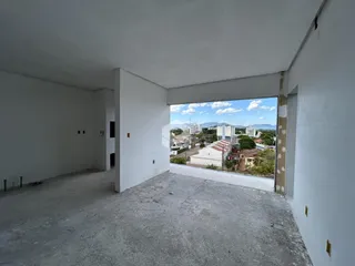 Espaço interno de uma residência com paredes brancas e piso de concreto.