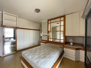 Quarto com armários brancos e cabeceira de madeira.