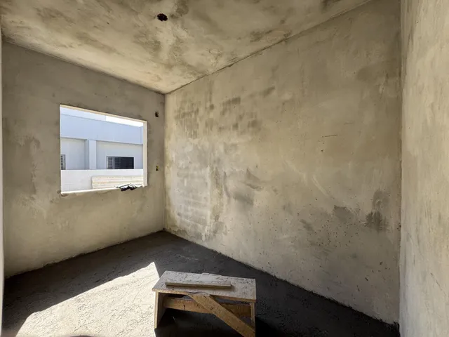 Foto de um cômodo vazio com paredes brancas e piso de concreto.