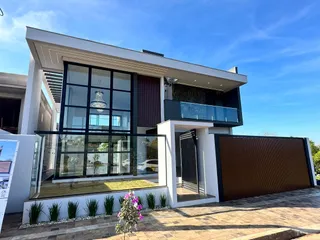 Fachada moderna de uma residência em Lajeado, Brasil, apresentando grandes janelas e uma varanda no andar superior.