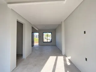 Hall de entrada com paredes brancas e piso de concreto.