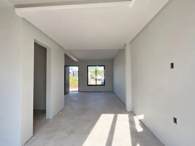 Hall de entrada com paredes brancas e piso de concreto.