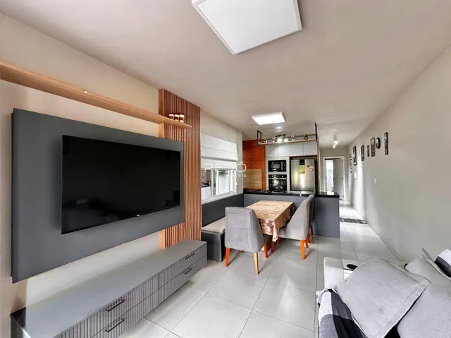 Interior de uma sala de estar com área de cozinha em um apartamento.