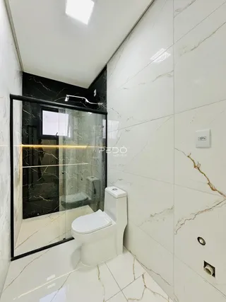Banheiro moderno com revestimento em mármore branco e detalhes em preto.