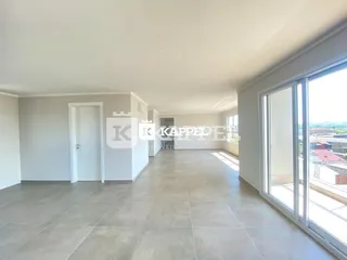 Ambiente interno com paredes brancas e piso claro, com grande janela de vista.