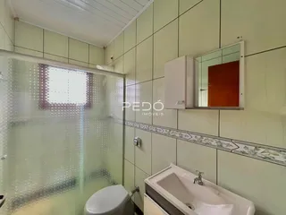 Banheiro com revestimento de azulejos nas paredes e box de vidro.