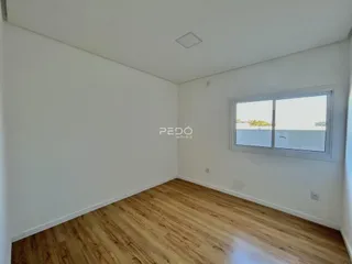 Ambiente interno de uma sala com piso de madeira clara e janela.