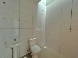 Banheiro com paredes brancas e revestimento cerâmico.