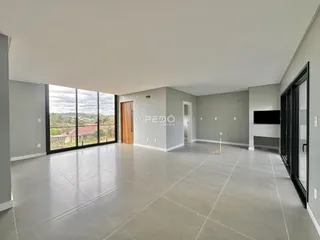 Sala de estar ampla com piso de porcelanato claro e porta de vidro.