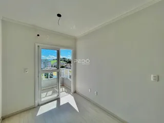 Vista interna de um cômodo com porta de vidro abrindo para uma área externa.