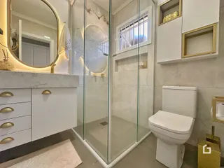 Banheiro moderno com box de vidro e bancada de mármore.