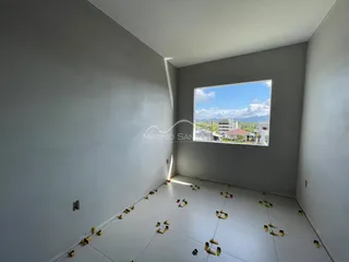 Ambiente interno vazio com piso em construção e vista para a paisagem externa.