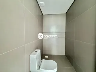 Foto de um banheiro com revestimento de azulejos claros e vaso sanitário branco.