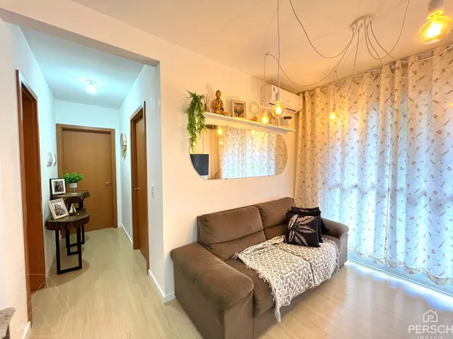 Sala de estar com sofá e cortinas claras em um apartamento.