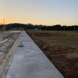 Vista de um caminho de concreto que leva a um campo aberto.