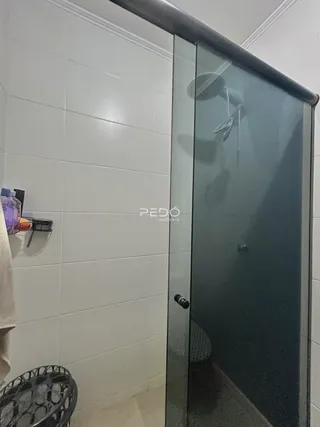 Foto da parede de um banheiro com revestimento cerâmico e box de vidro.