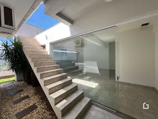 Degraus externos de concreto levam à área interna da residência através de uma porta de vidro.