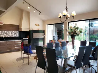 Uma sala de jantar com mesa de vidro e cadeiras escuras em um apartamento.
