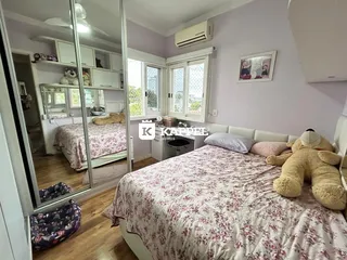 Quarto com cama e armários brancos em um ambiente claro.