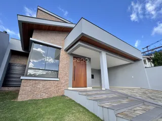 Fachada moderna de uma residência em Lajeado, Brasil, com revestimento de tijolo e detalhes em madeira.