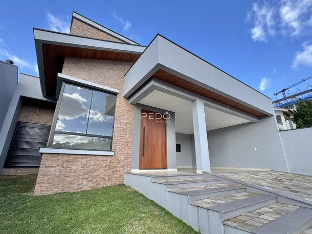 Fachada moderna de uma residência em Lajeado, Brasil, com revestimento de tijolo e detalhes em madeira.