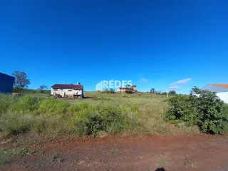 Paisagem de campo com uma casa rústica no meio da vegetação.