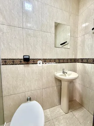 Banheiro com revestimento de azulejos brancos e vaso sanitário.