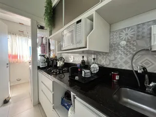 Foto da cozinha com armários brancos e bancada escura.
