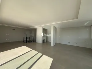Ambiente interno de uma sala ampla com piso de cerâmica e paredes brancas.