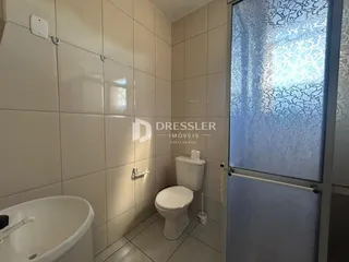 Banheiro com revestimento cerâmico nas paredes e louças sanitárias brancas.
