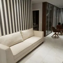 Foto de uma sala de estar com um sofá claro e parede listrada.
