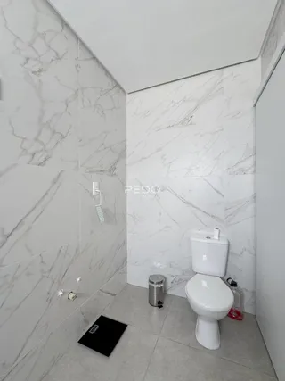 Banheiro com revestimento de mármore nas paredes e piso claro.