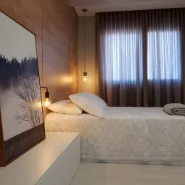 Foto de um quarto com cama de casal e roupa de cama branca.