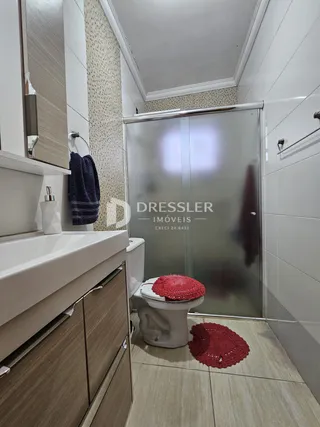 Interior de um banheiro com box de vidro e louças sanitárias.