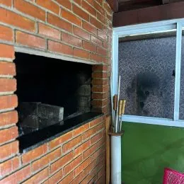 Parede de tijolos vermelhos com uma abertura de lareira.