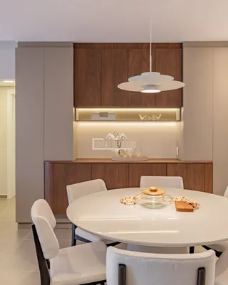 Uma mesa de jantar branca com cadeiras brancas em um ambiente interno.