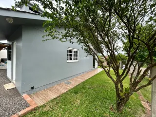 Foto da fachada de uma casa com deck de madeira e área gramada.